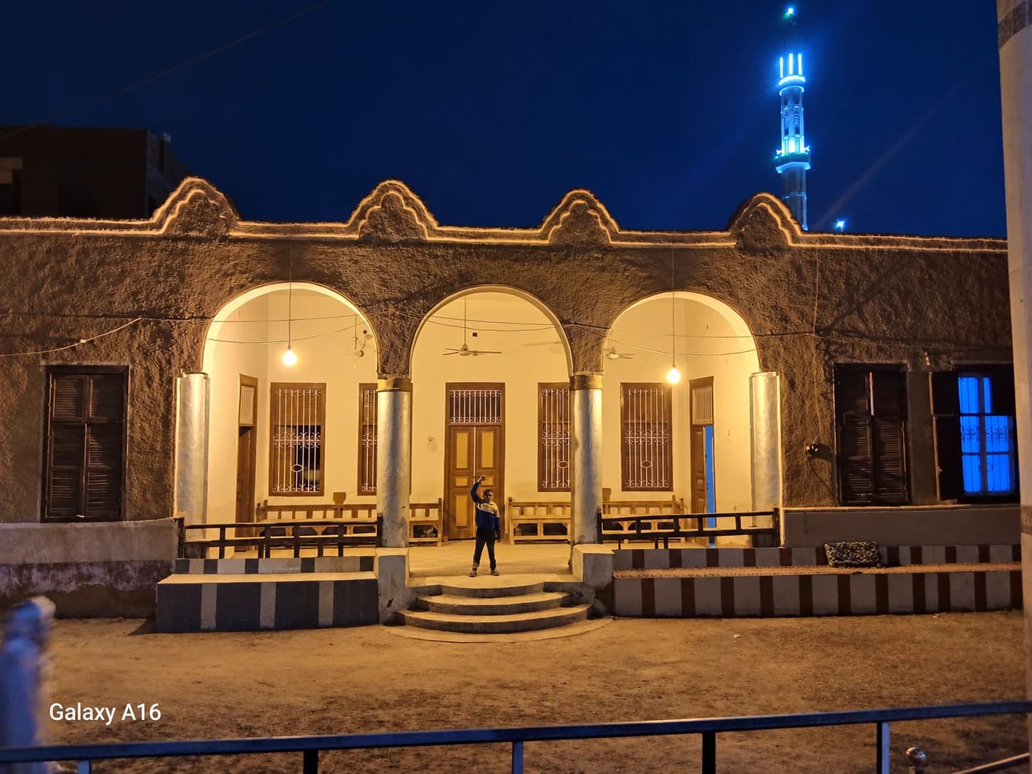واجهة ديوان آل يونس ليلًا كما عرّفتها المادة المرسلة، بأقواسها الثلاثة ومقاعدها في الأوسط قمولا